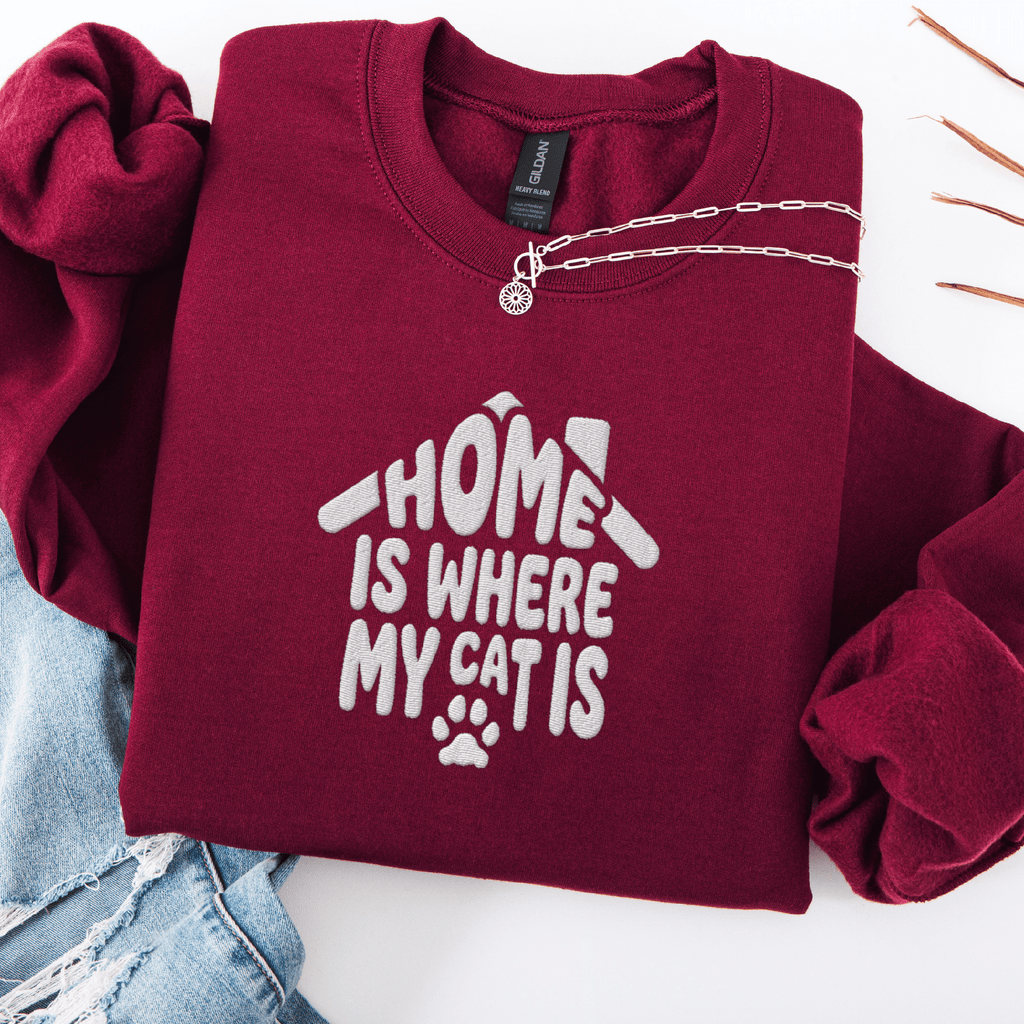 Maroon embroidered cat sweatshirt with the phrase “Home Is Where My Cats Are” shown folded flat