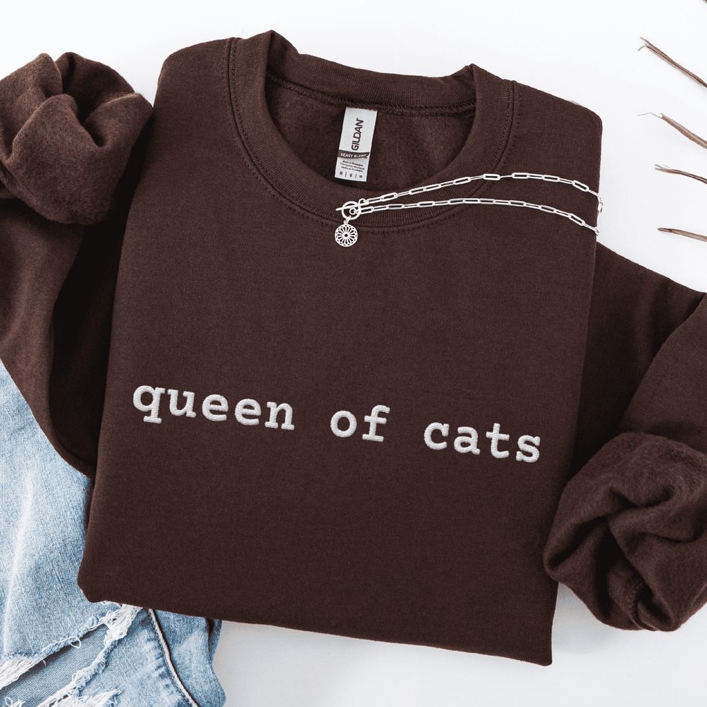 Dark Chocolate embroidered cat sweatshirt with the phrase “queen of cats” shown folded flat