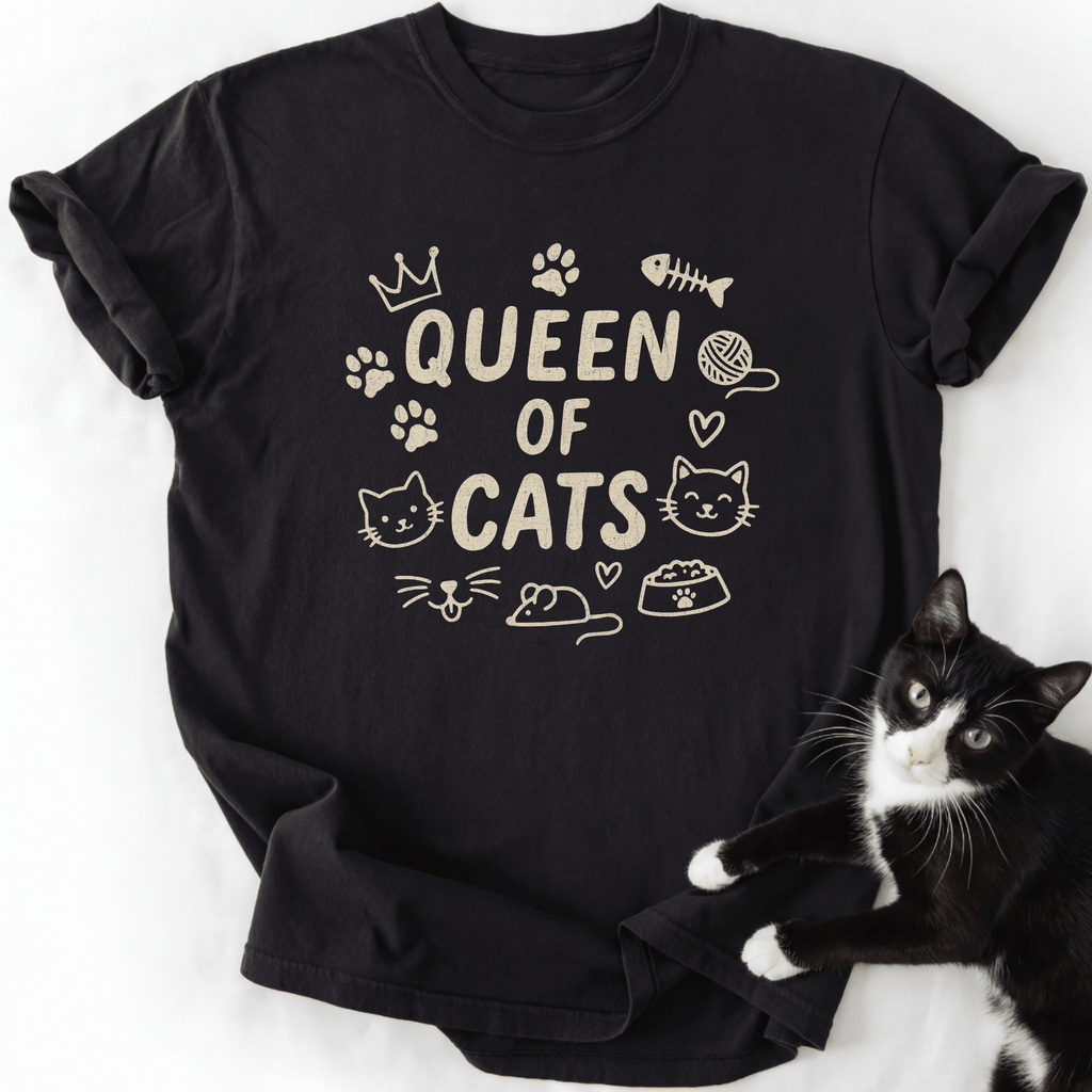 Black Queen of Cats cat t shirt with cat-themed doodle icons shown laid flat with a tuxedo cat beside it