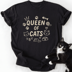 Black Queen of Cats cat t shirt with cat-themed doodle icons shown laid flat with a tuxedo cat beside it