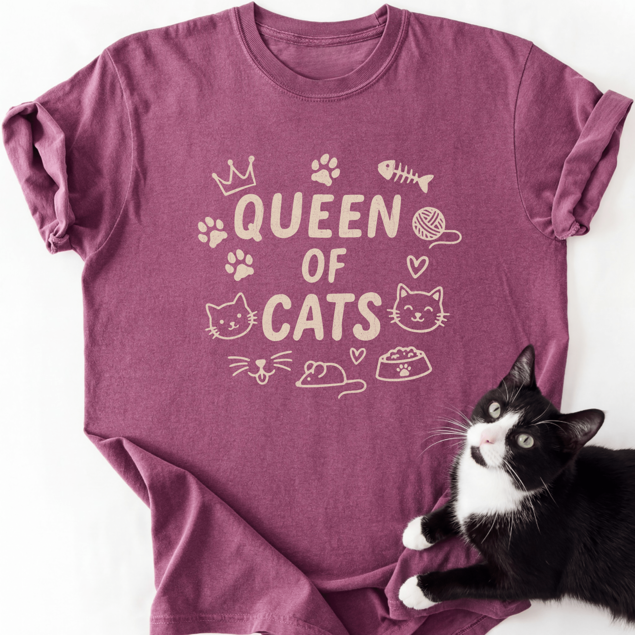 Berry Queen of Cats cat t shirt with cat-themed doodle icons shown laid flat with a tuxedo cat beside it