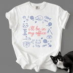 White funny cat t shirt with I'll be in my office text and pastel cat office illustration, shown flat with a black cat beside it