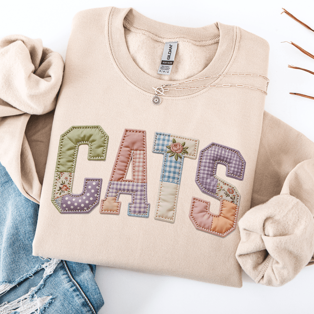 Sand graphic sweatshirt with CATS faux patchwork lettering folded flat with jeans