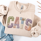 Sand graphic sweatshirt with CATS faux patchwork lettering folded flat with jeans