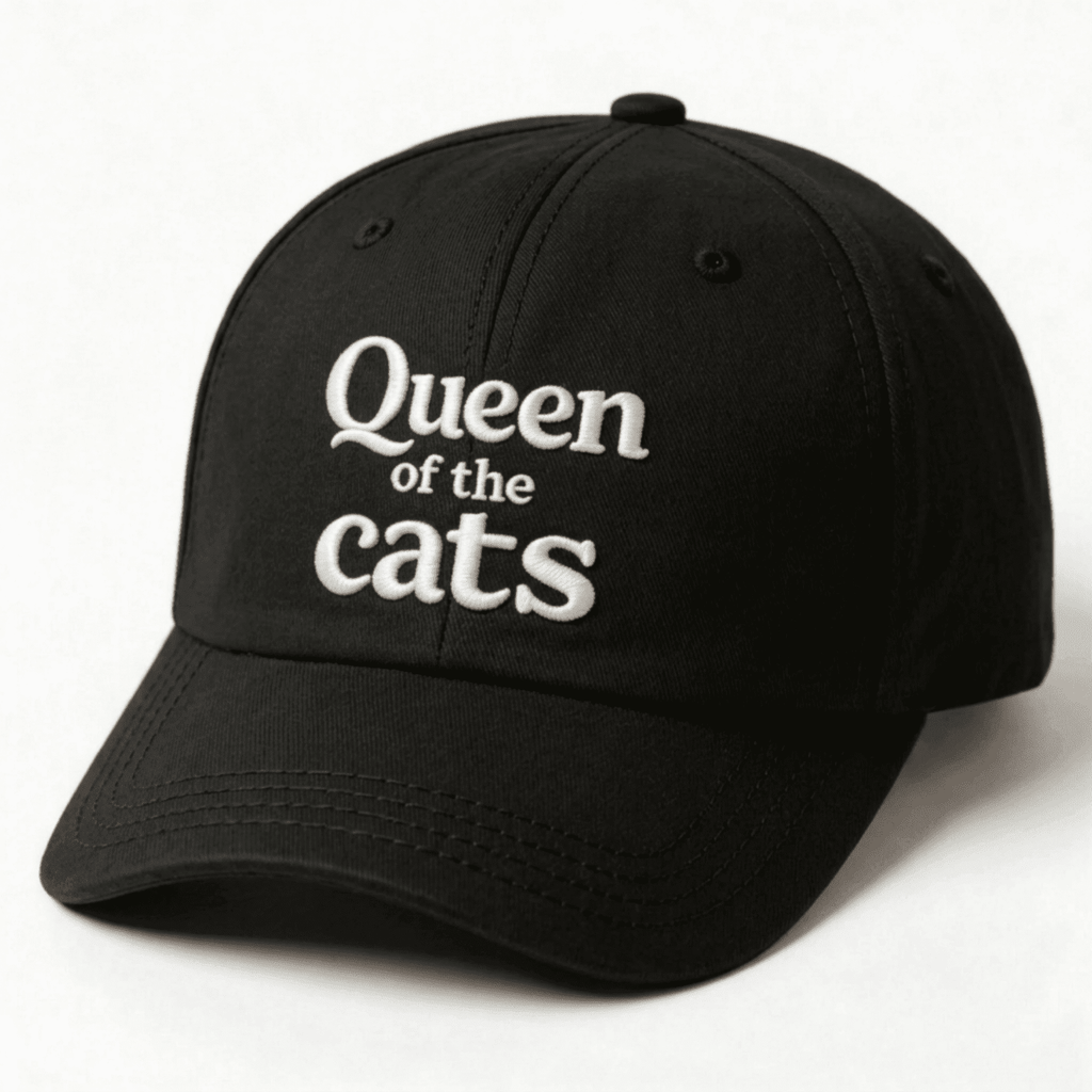 Black cap with white Queen of the Cats embroidery shown at an angle