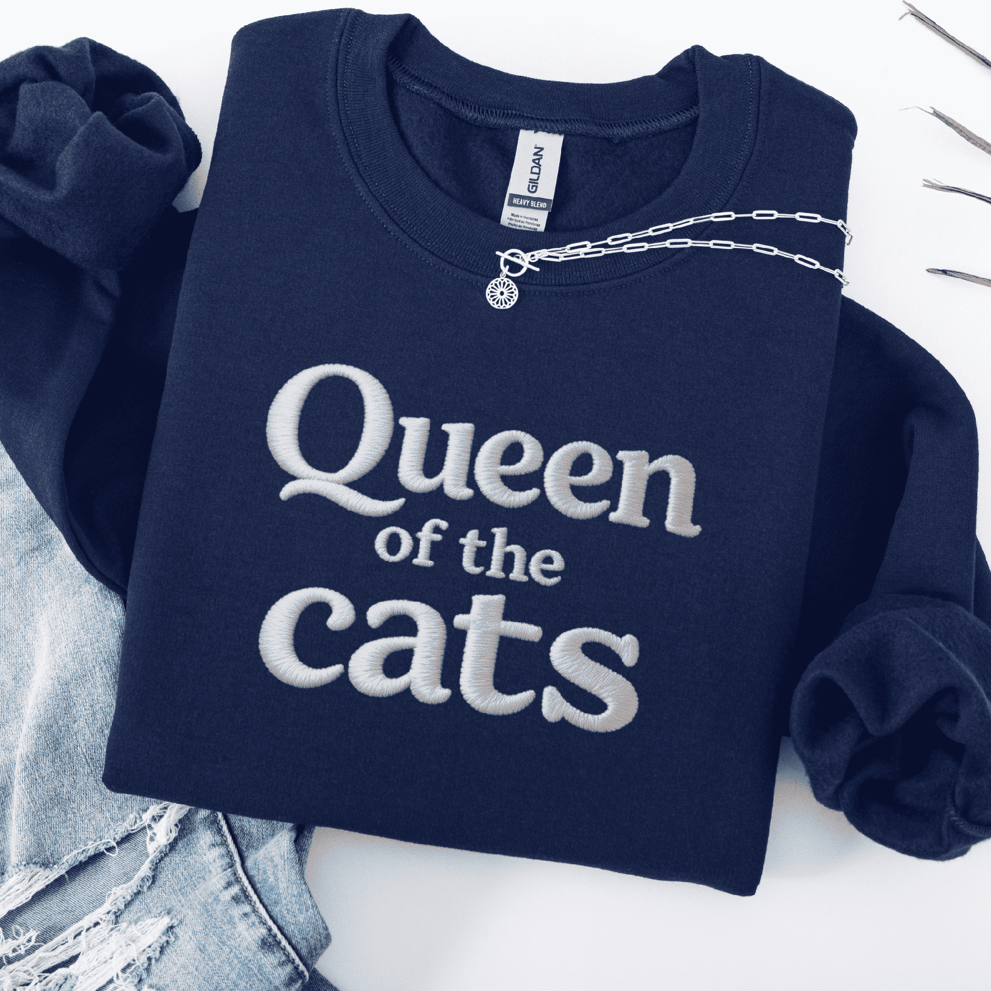 Navy cat embroidered sweatshirt with Queen of the Cats text shown folded