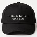 Front view of a black embroidered cap with the phrase life is better with cats in white lettering