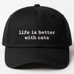 Front view of a black embroidered cap with the phrase life is better with cats in white lettering