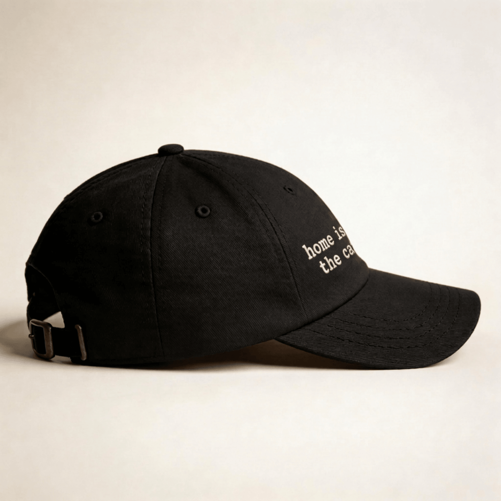 Side view of a black embroidered cap with curved brim and adjustable back strap