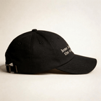 Side view of a black embroidered cap with curved brim and adjustable back strap