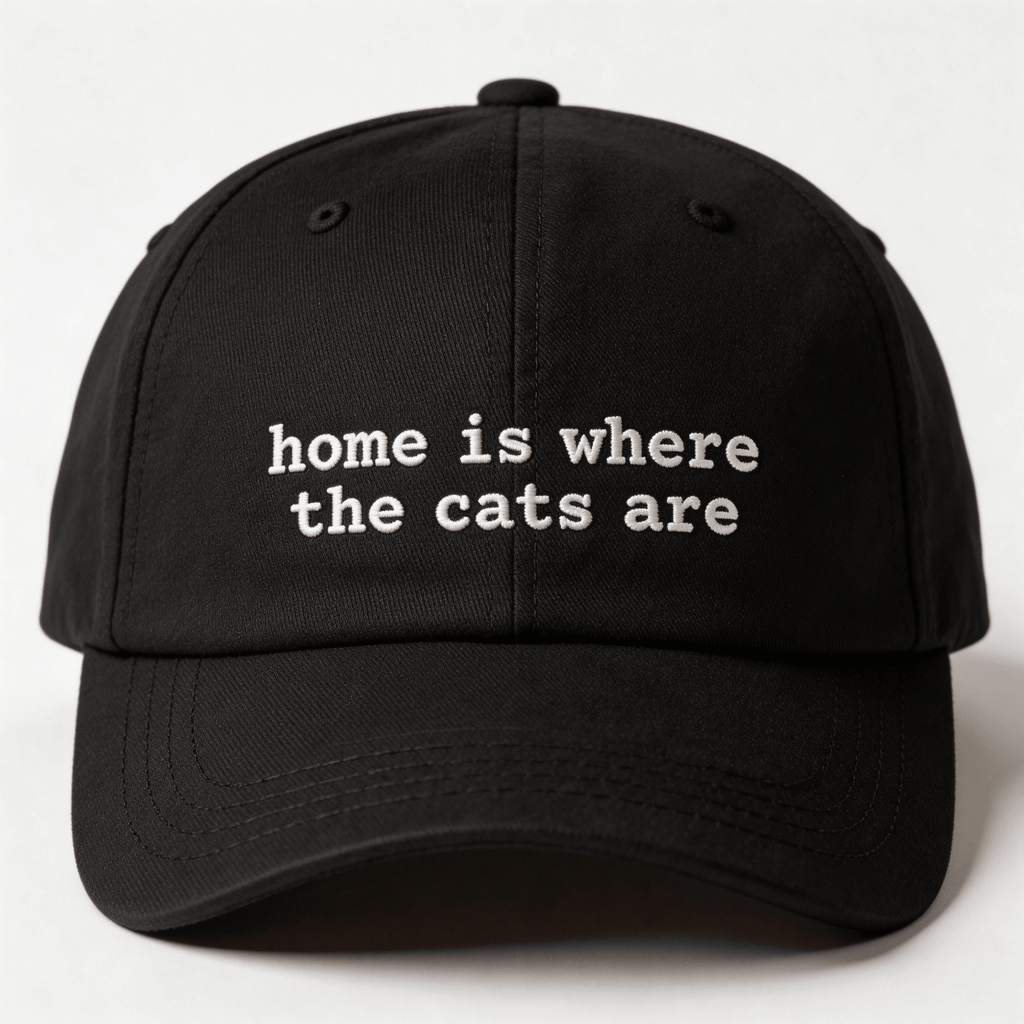 Front view of a black embroidered cap with the phrase home is where the cats are in white lettering