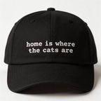 Front view of a black embroidered cap with the phrase home is where the cats are in white lettering
