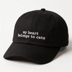 Angled front view of a black embroidered cap with my heart belongs to cats text on the front