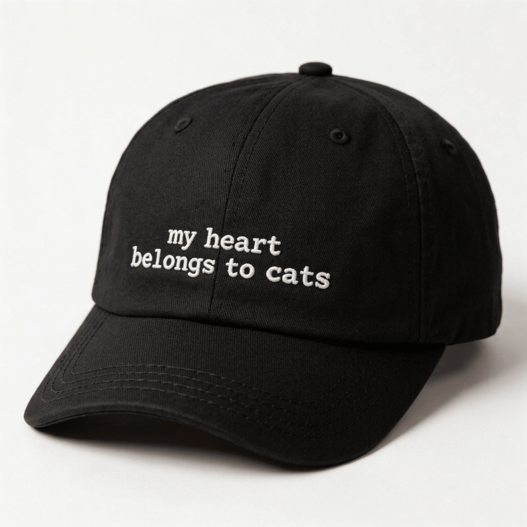 Angled front view of a black embroidered cap with my heart belongs to cats text on the front