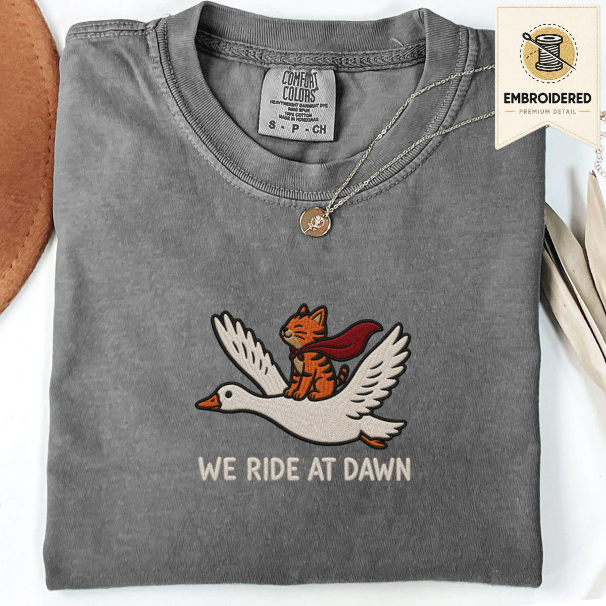 Pepper gray embroidered funny cat t shirt with We Ride At Dawn text and winged orange cat design