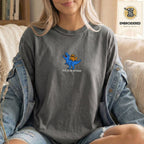 Woman wearing a pepper gray embroidered funny cat t shirt with This Is An Outrage cat design while sitting indoors in a denim jacket