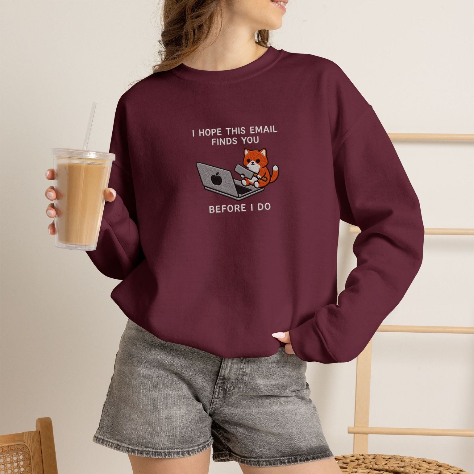 Model wearing maroon Before I Do embroidered cat sweatshirt, holding iced coffee
