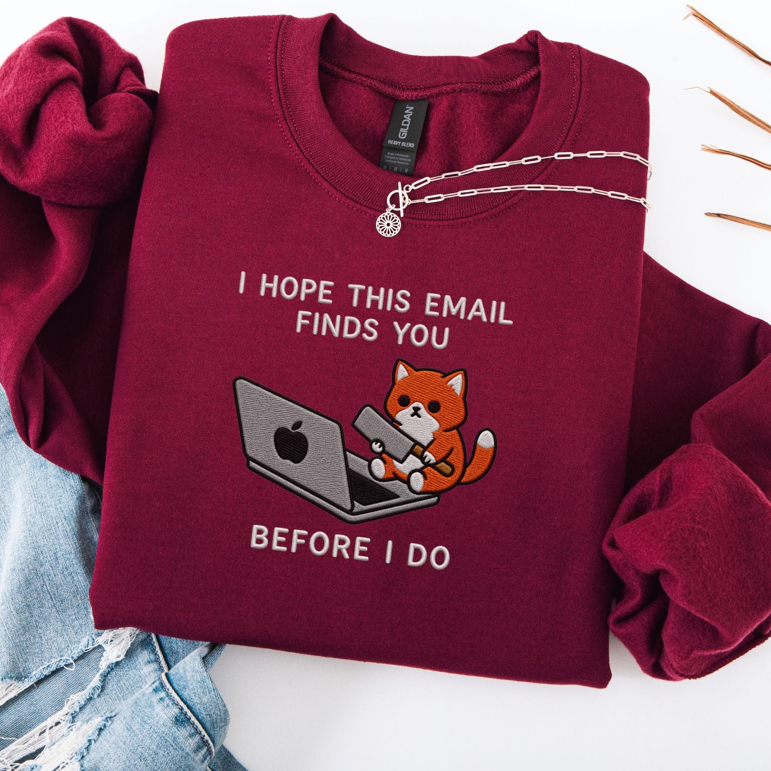 Maroon embroidered cat sweatshirt with orange cat at a laptop, I Hope This Email Finds You Before I Do text, flat lay