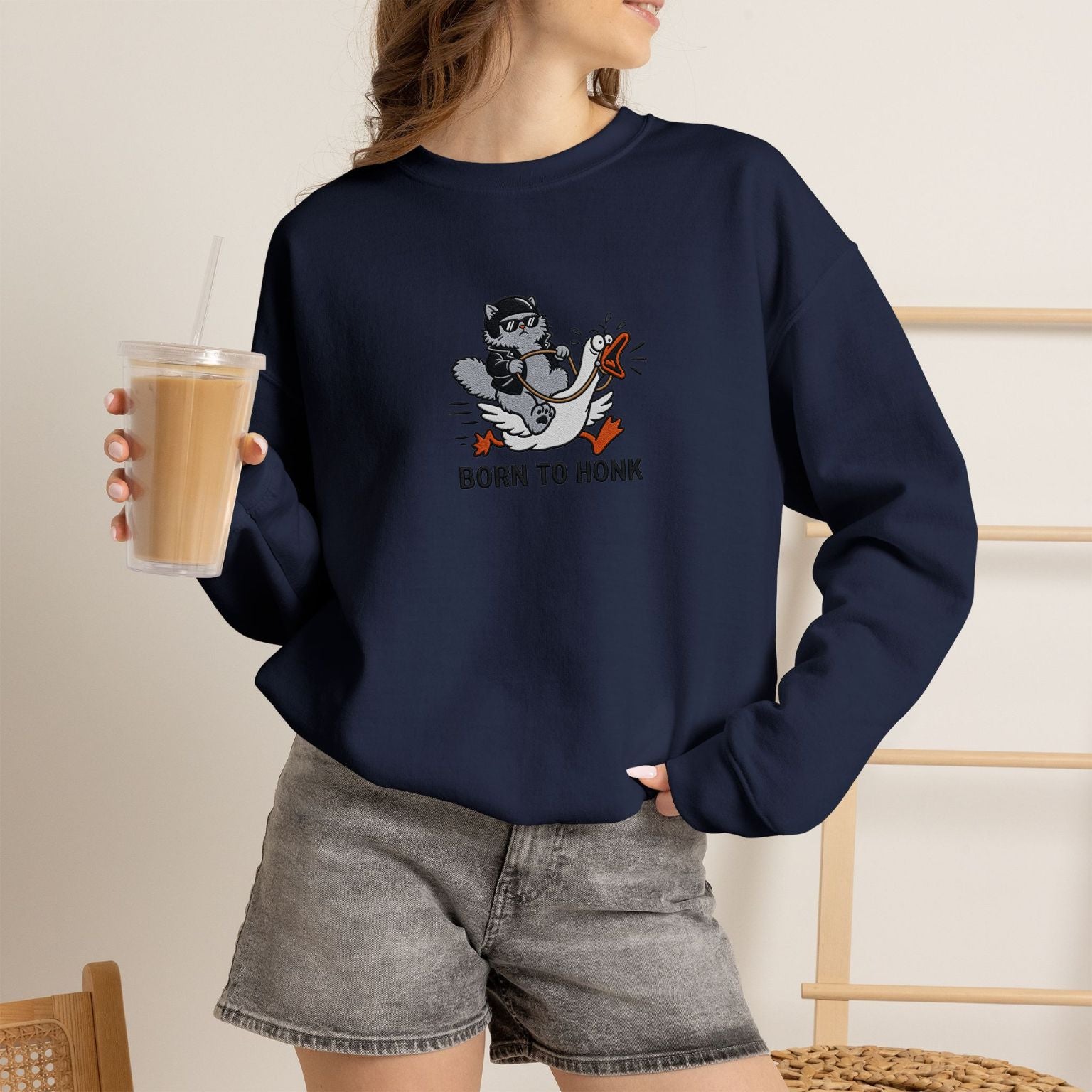 Model wearing navy Born to Honk embroidered cat sweatshirt, holding iced coffee
