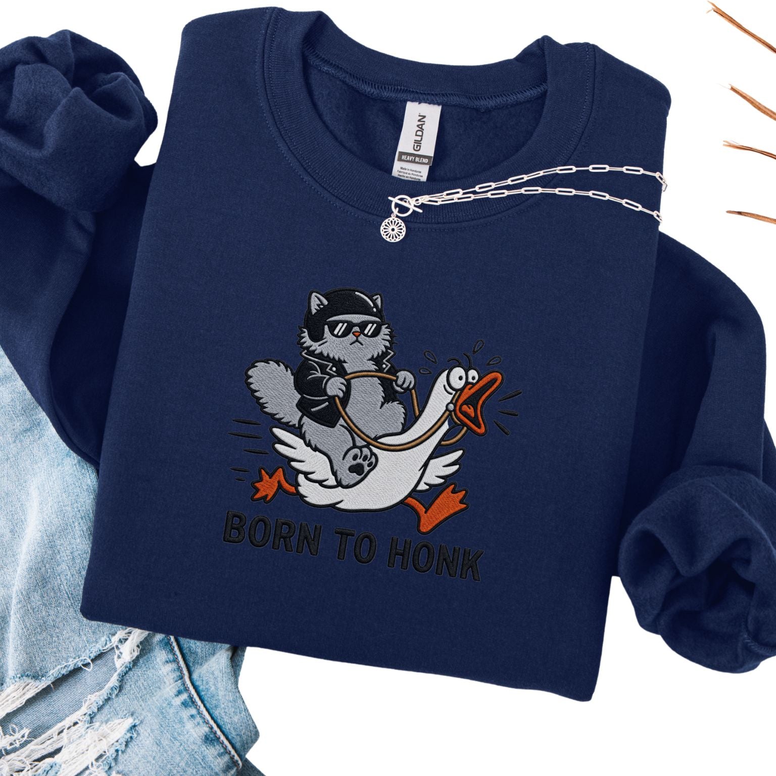 Navy embroidered cat sweatshirt with cool grey cat in sunglasses riding a goose, Born to Honk text, flat lay