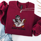 Maroon embroidered cat sweatshirt with cool grey cat in sunglasses riding a panicking white goose, Born to Honk text, flat lay