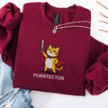Maroon embroidered cat sweatshirt with heroic orange tabby in red cape holding sword aloft, Purrtector text, flat lay