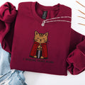 Maroon embroidered cat sweatshirt with medieval orange tabby holding a sword, I Require Treats M'Lord text, flat lay