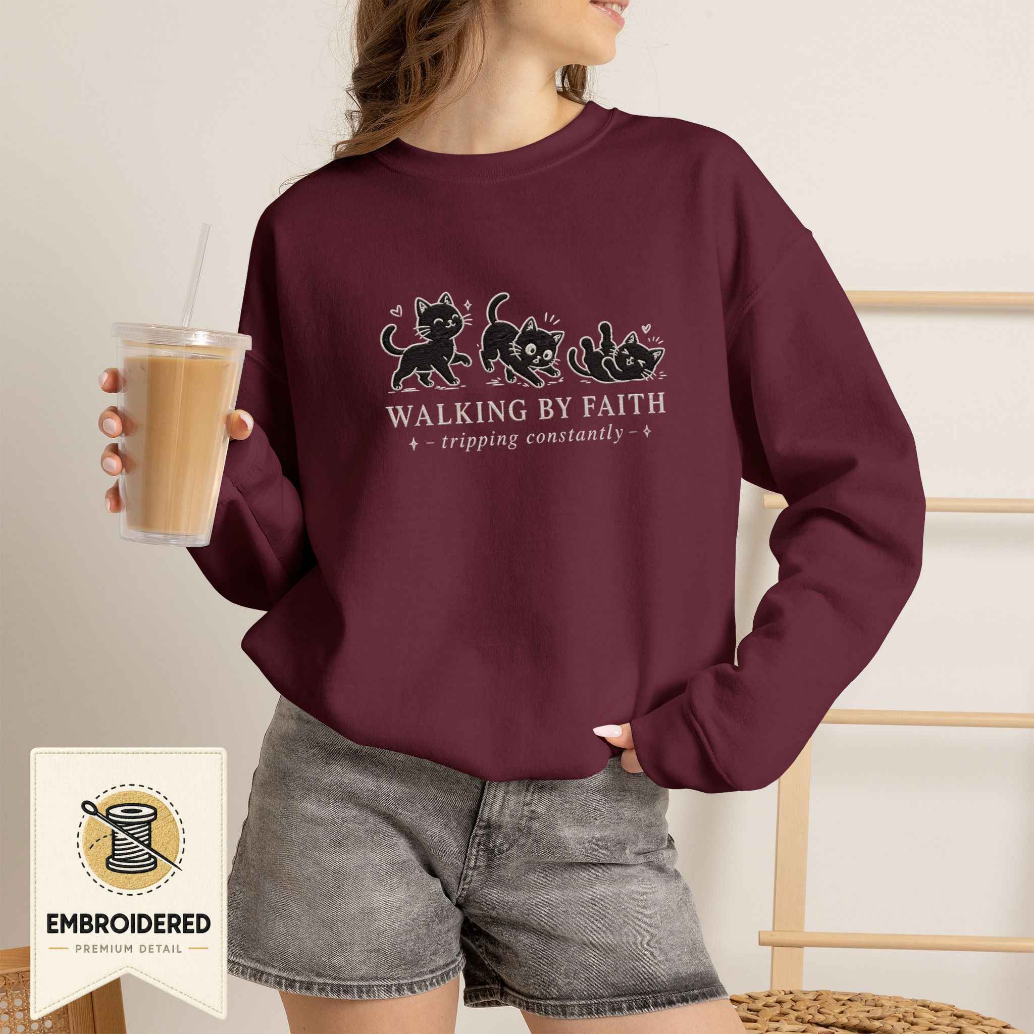Woman wearing a maroon embroidered Walking by Faith cat sweatshirt