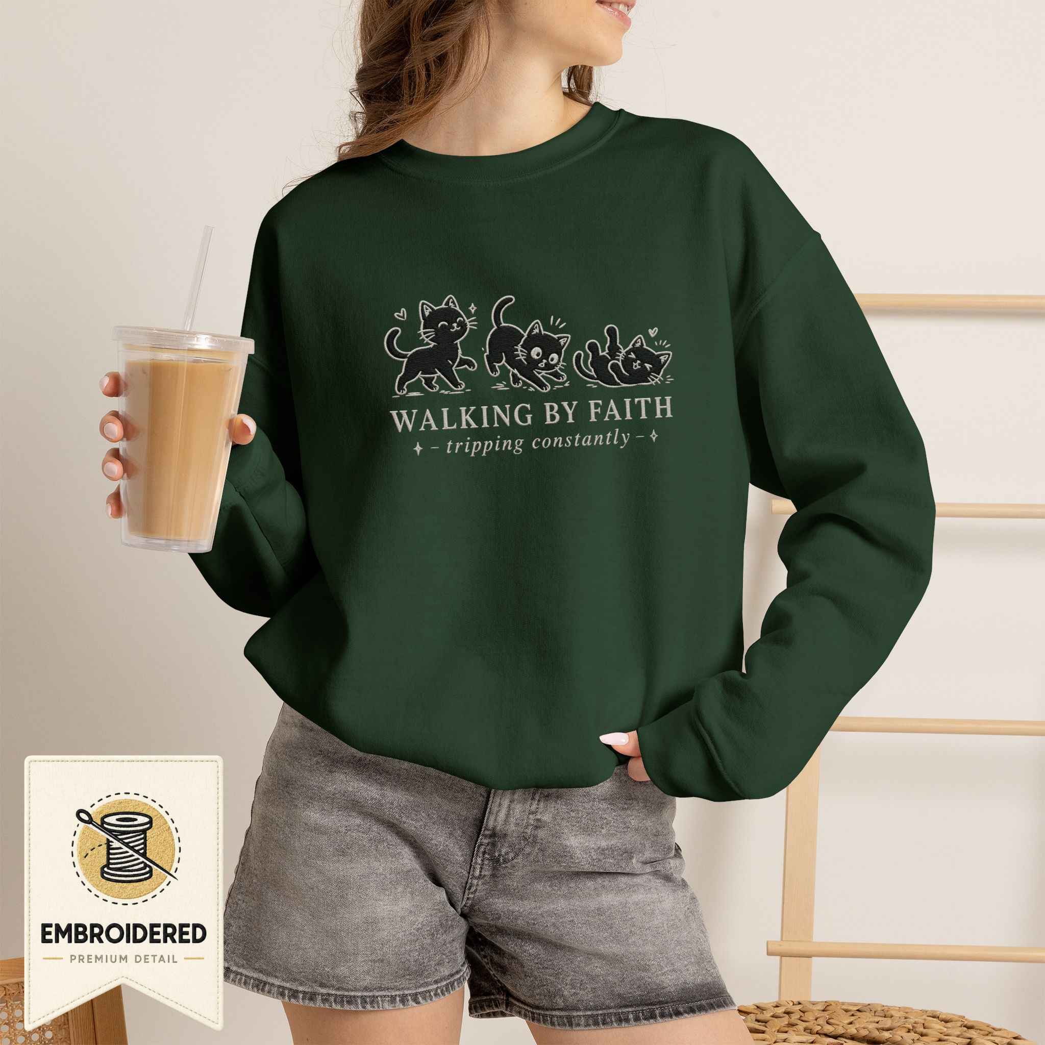 Woman wearing a forest green embroidered Walking by Faith cat sweatshirt