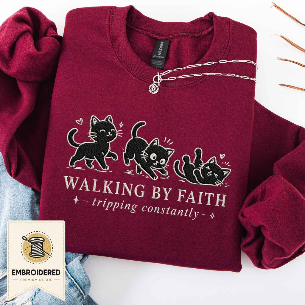 Maroon embroidered cat sweatshirt with a small Walking by Faith design and walking cats, shown flat