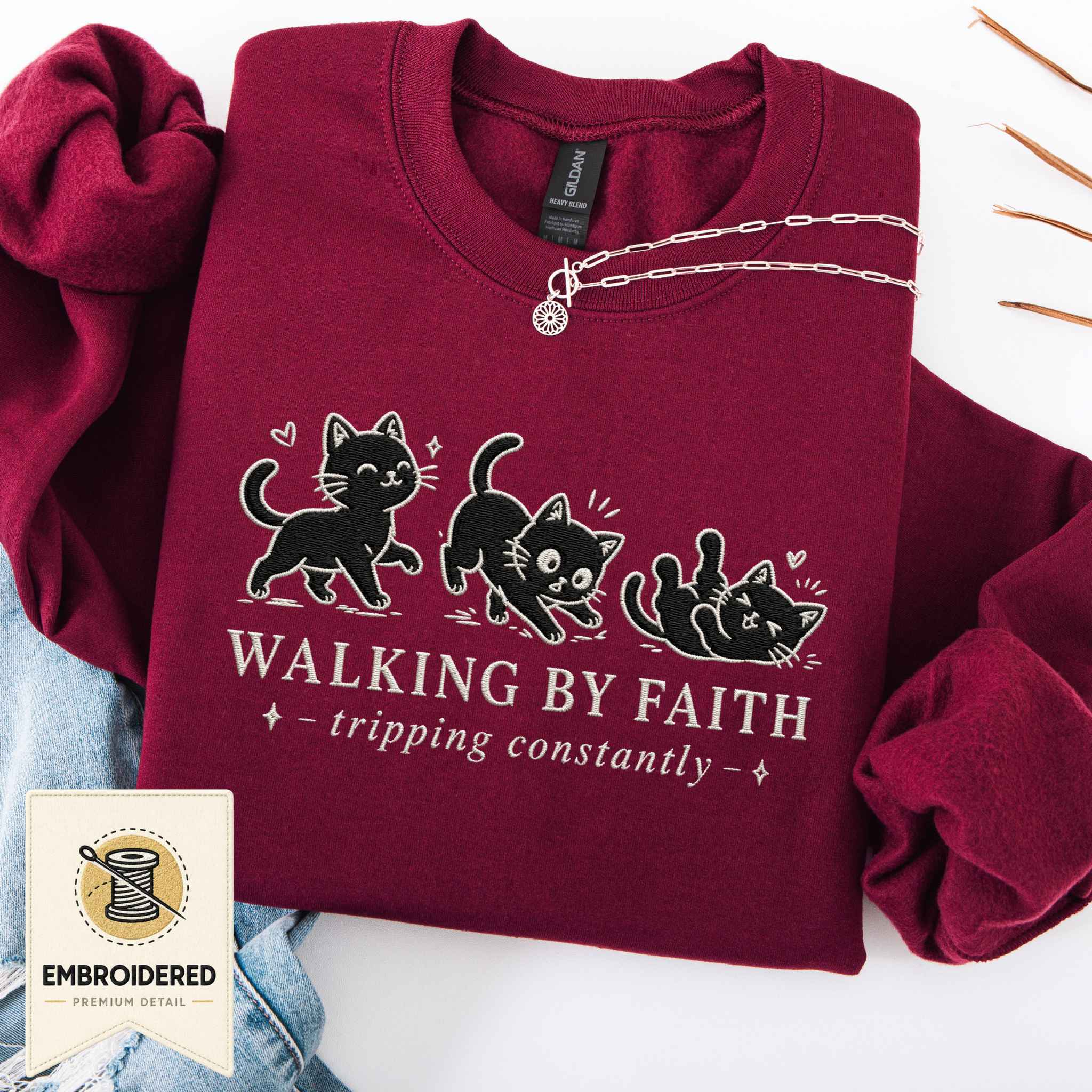 Maroon embroidered cat sweatshirt with a small Walking by Faith design and walking cats, shown flat