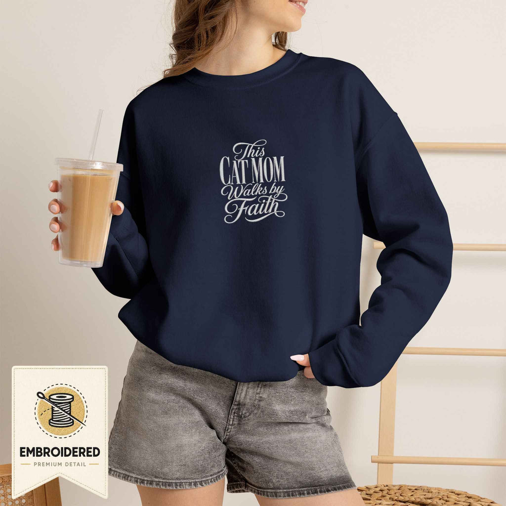 Woman wearing a navy embroidered This Cat Mom Walks by Faith cat sweatshirt