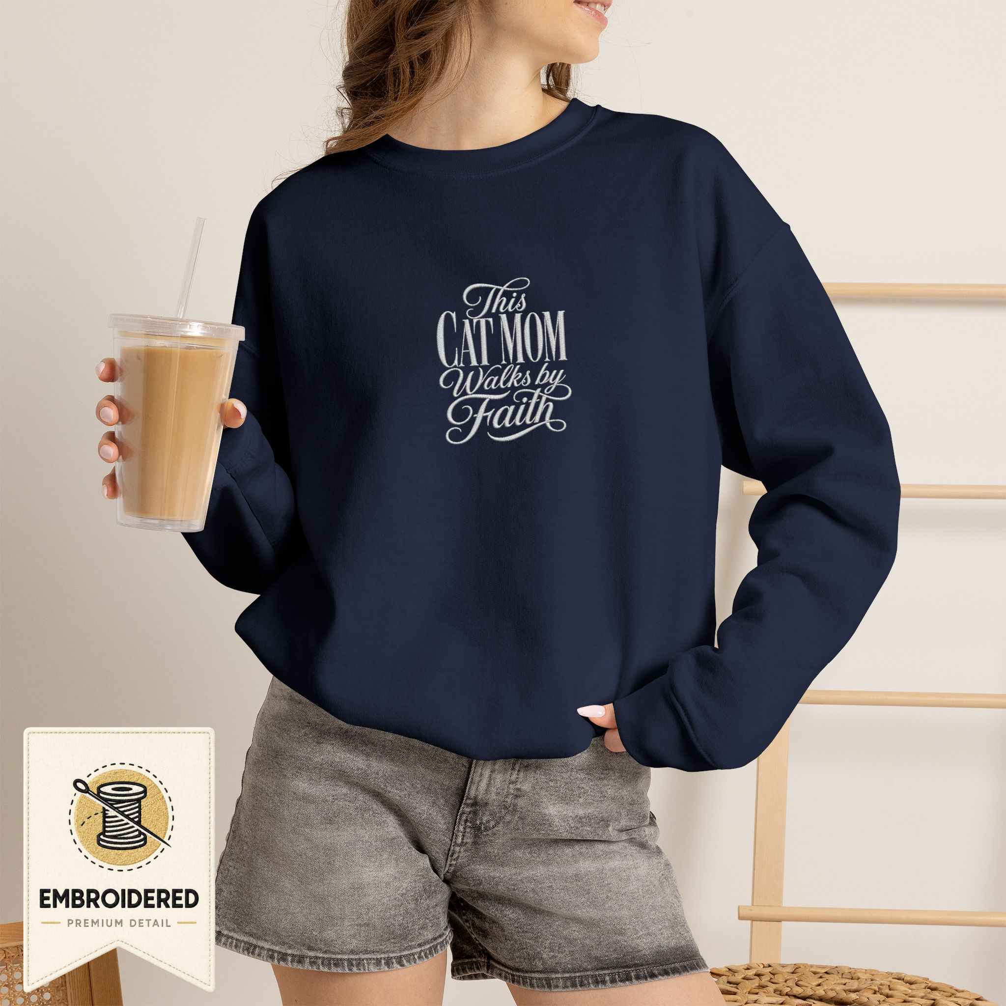 Woman wearing a navy embroidered This Cat Mom Walks by Faith cat sweatshirt