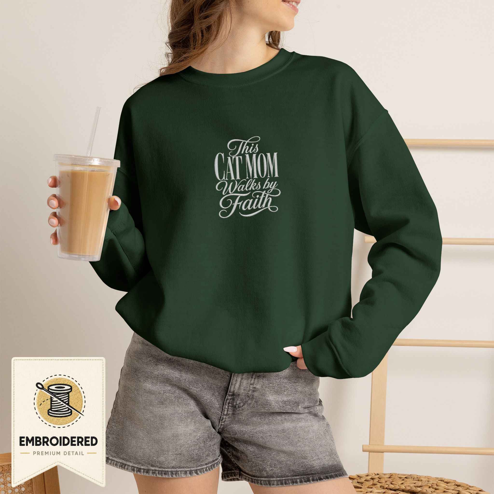 Woman wearing a forest green embroidered This Cat Mom Walks by Faith cat sweatshirt