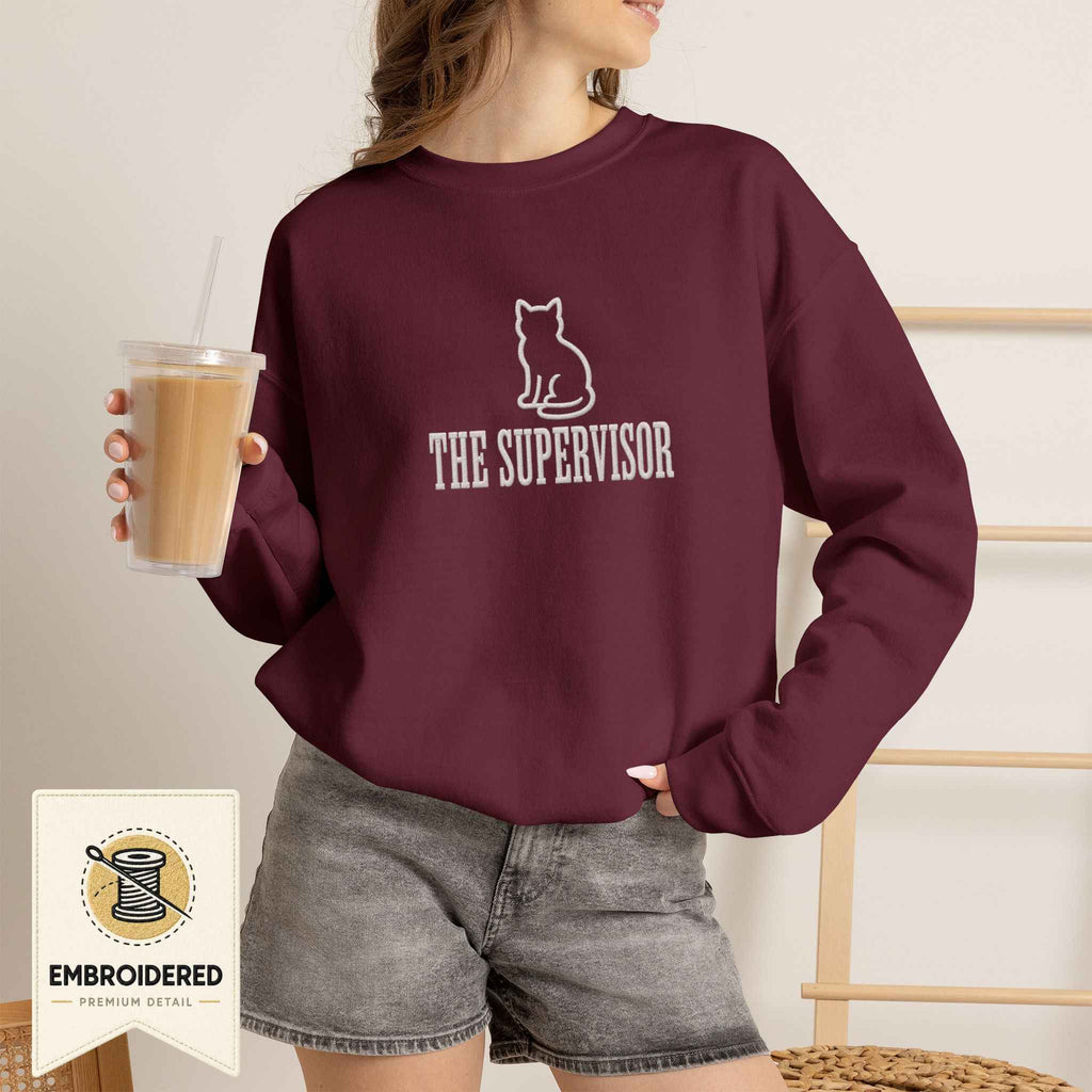 Woman wearing a maroon embroidered The Supervisor cat sweatshirt
