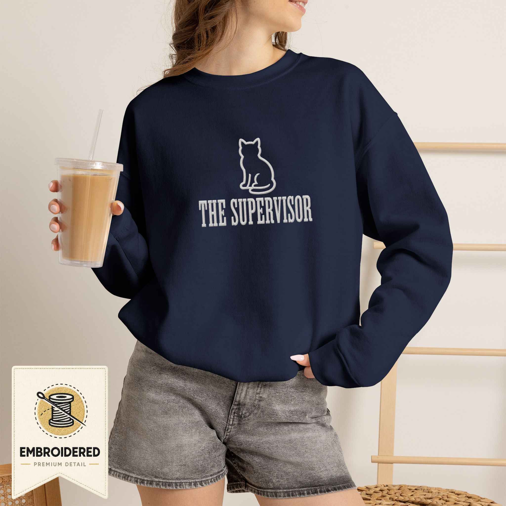 Woman wearing a navy embroidered The Supervisor cat sweatshirt