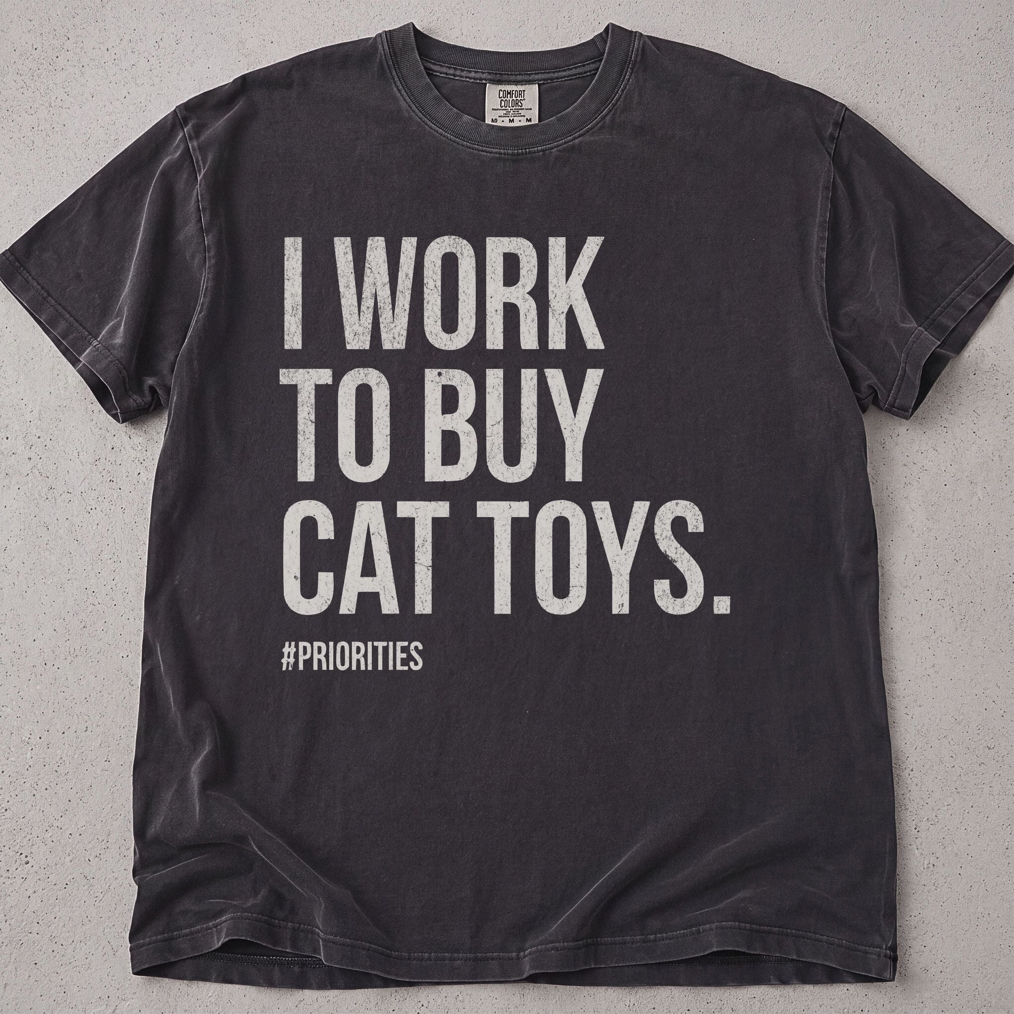 Pepper brown cat t-shirt with I Work To Buy Cat Toys printed text graphic, funny cat lover tee on soft Comfort Colors cotton, flat lay front view