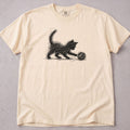 Ivory cat t-shirt with an illustration of a black kitten pouncing on a ball of yarn, cute cat lover tee on soft Comfort Colors cotton, flat lay front view