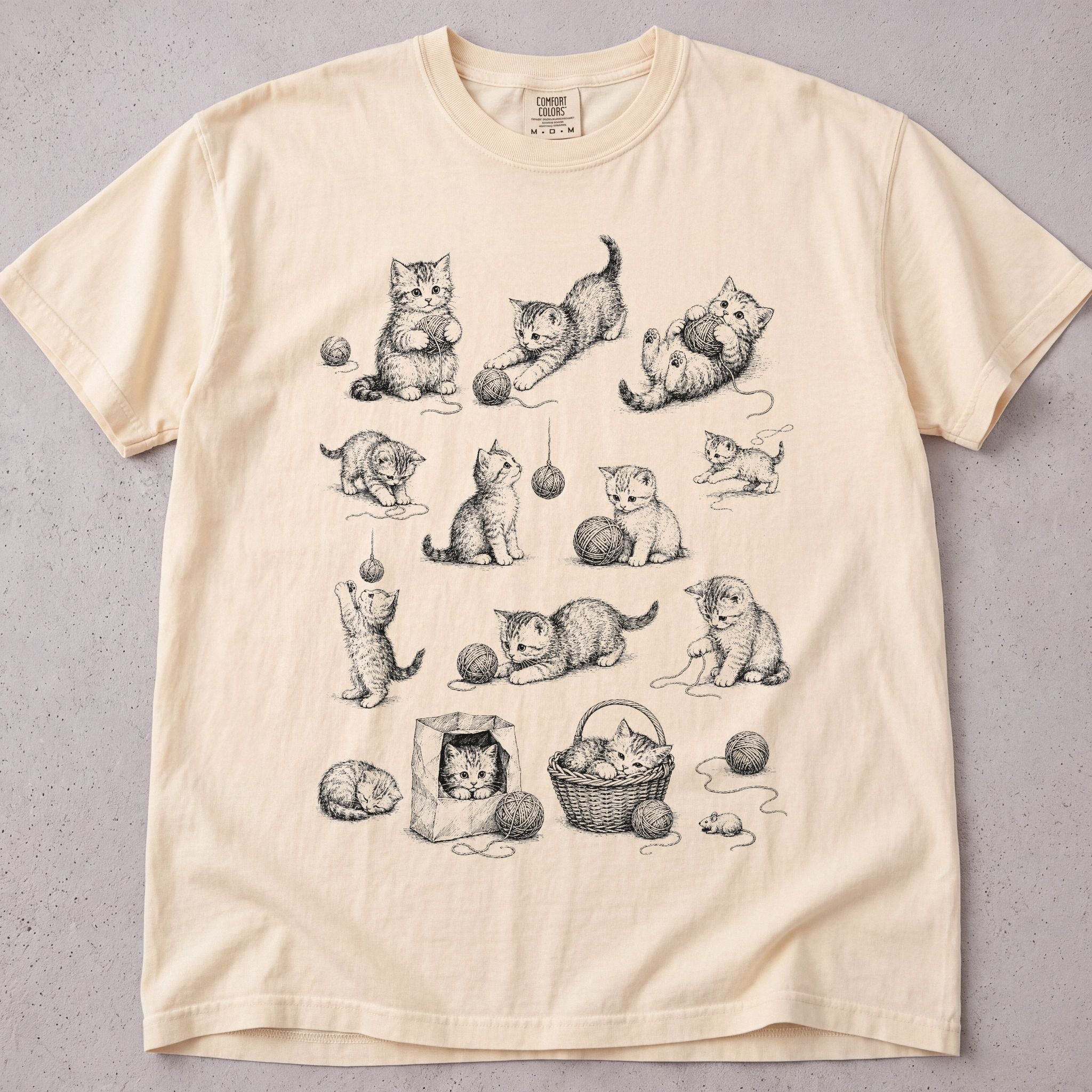 Ivory cat t-shirt with a hand-drawn illustration of kittens playing with yarn, cute cat lover tee on soft Comfort Colors cotton, flat lay front view