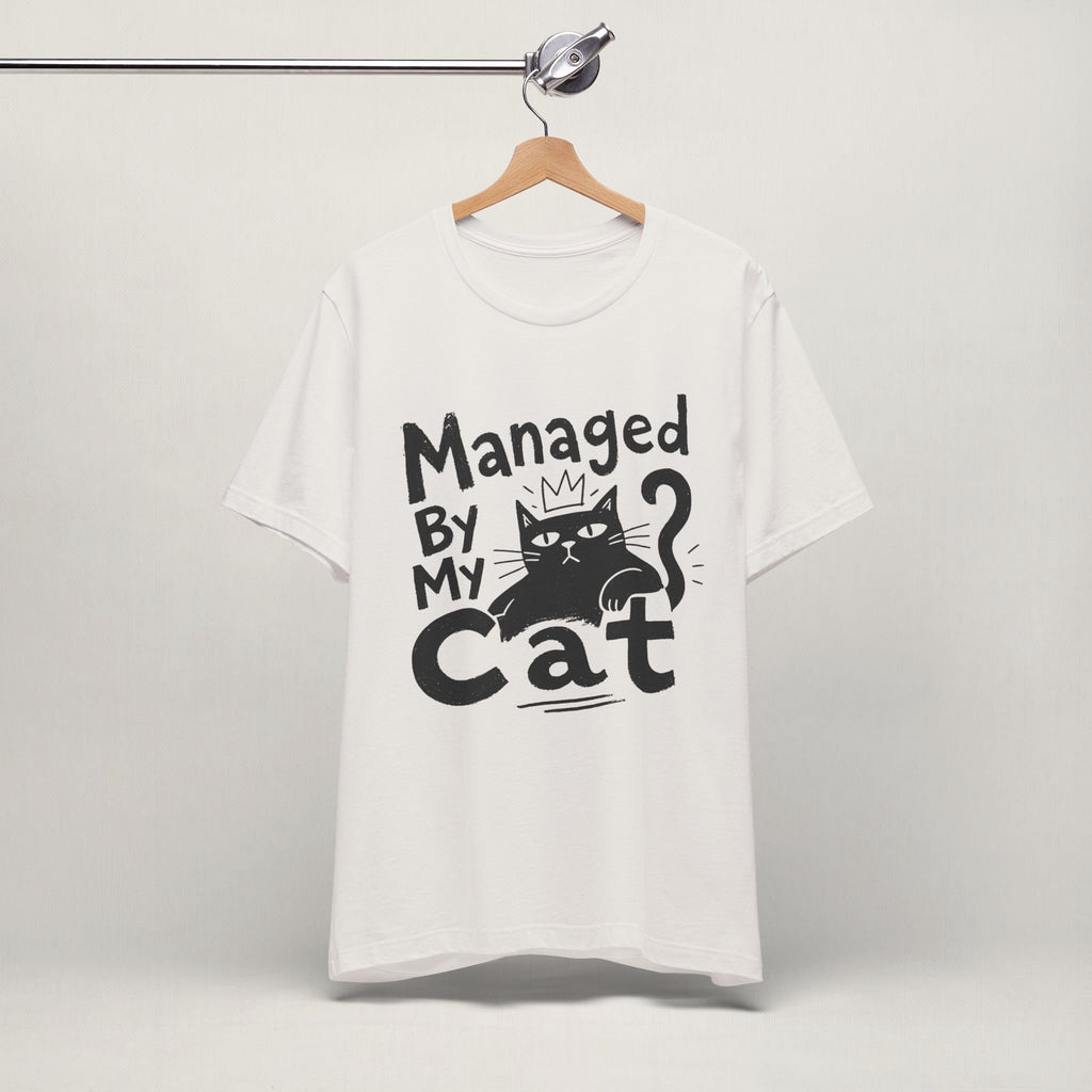 Vintage white Managed By My Cat t-shirt with paw icon hanging on a wooden hanger