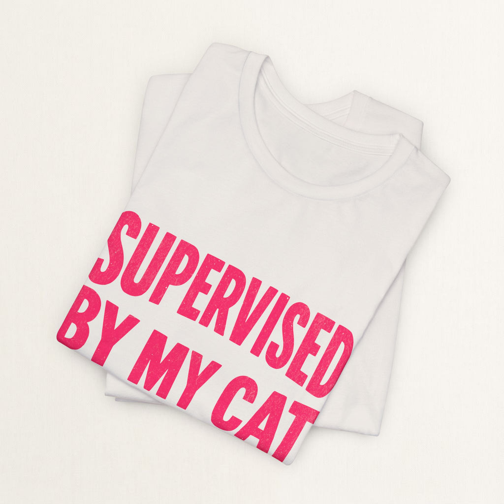 Folded vintage white Supervised By My Cat t-shirt with pink comic-style graphic