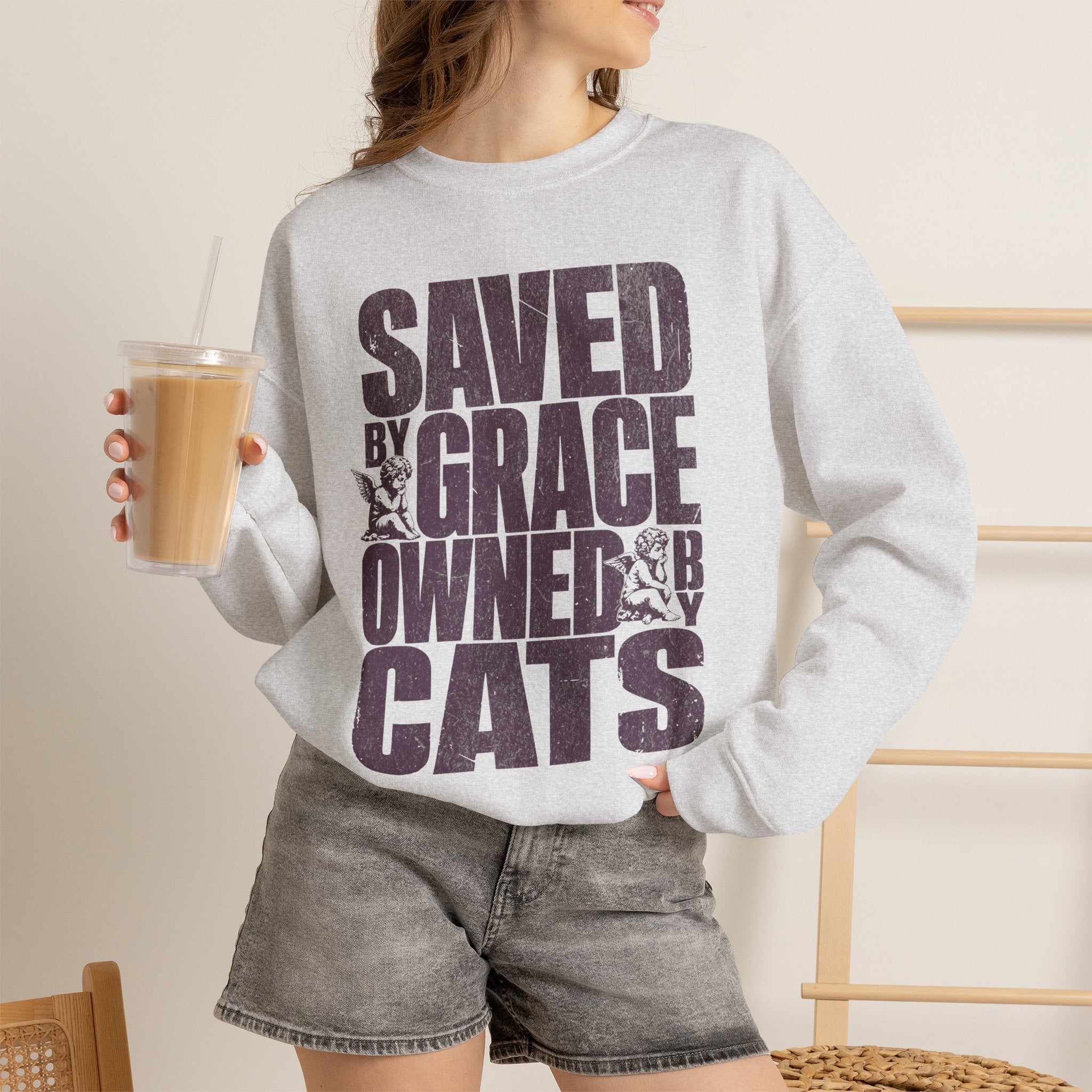 Woman wearing an ash Saved by Grace Owned by Cats printed cat sweatshirt