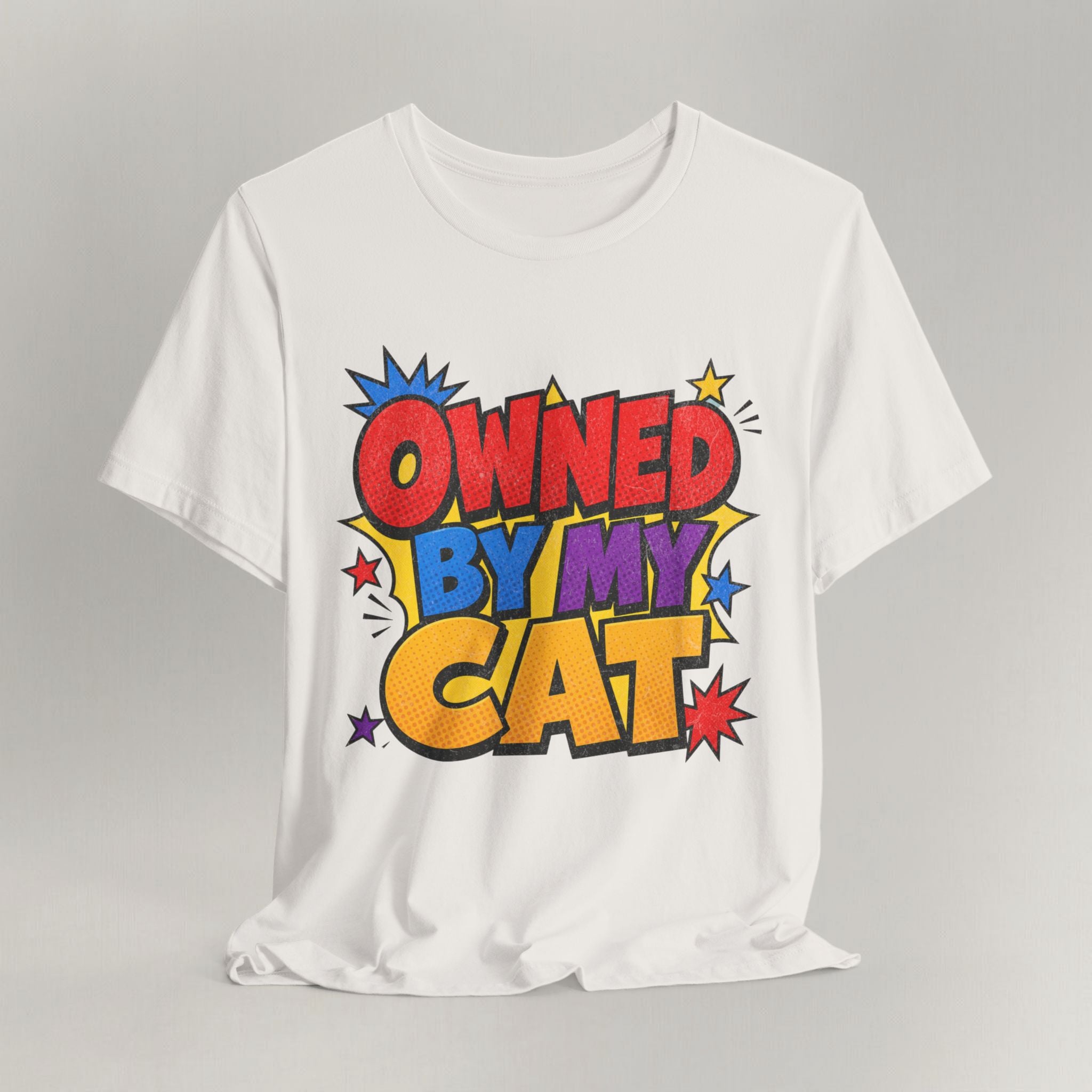 Vintage white t-shirt with bold colorful Owned By My Cat comic-style graphic and starbursts