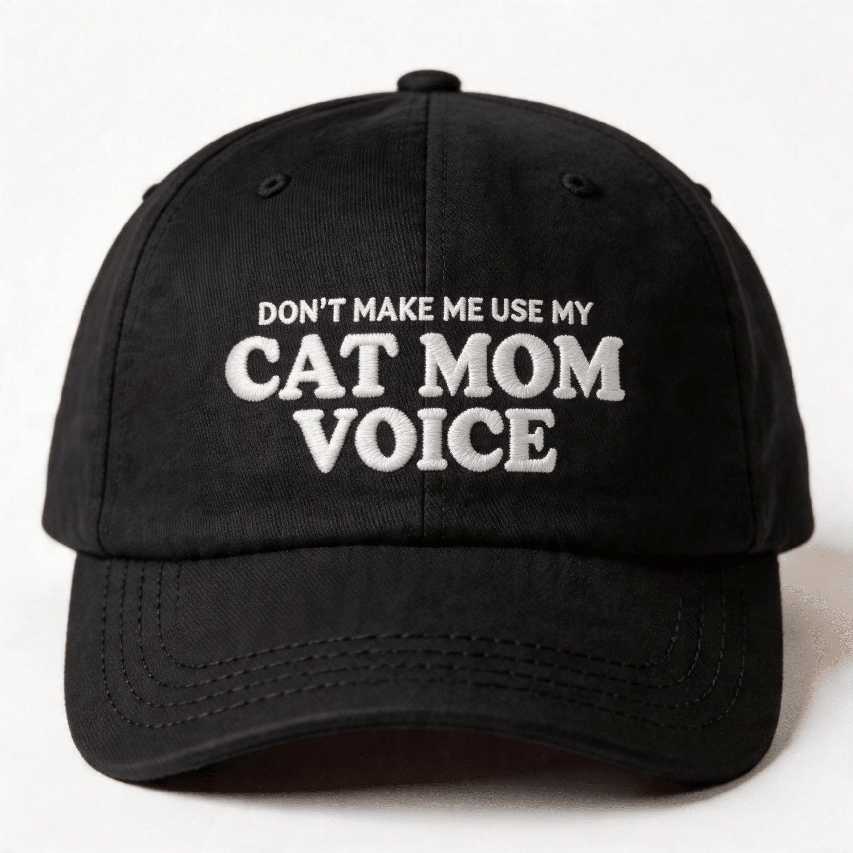 Black embroidered cap with white text that says “Don’t Make Me Use My Cat Mom Voice” shown from the front