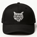 Black embroidered cap with white text that says “Home Is Where My Cat Is” shown from the front