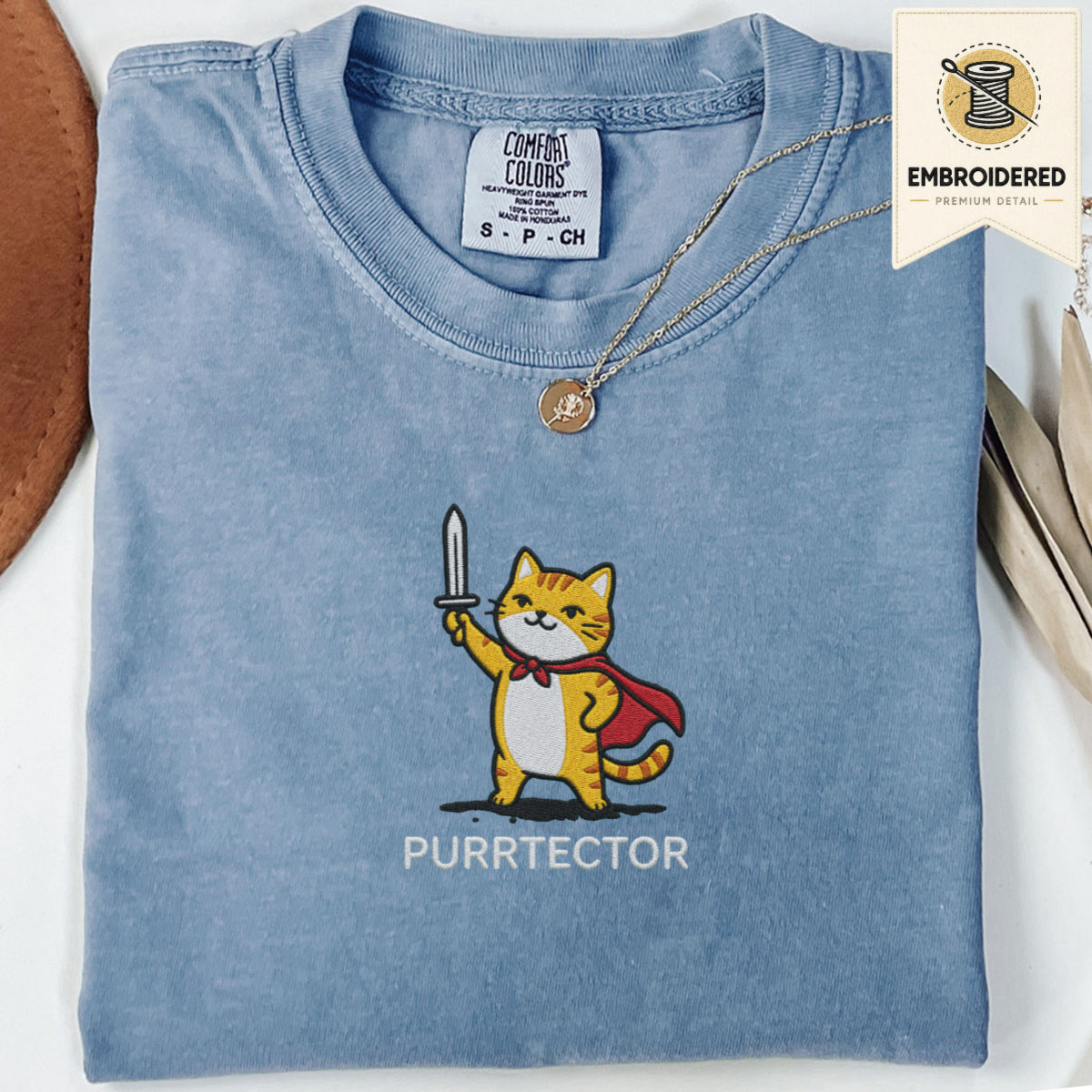 Blue jean embroidered cat tee with orange cat Purrtector design holding a sword