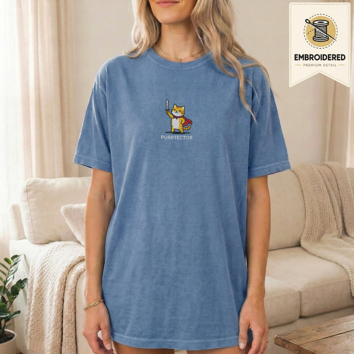 Woman wearing a blue jean embroidered funny cat t shirt with Purrtector orange cat design while standing indoors