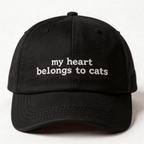Front view of a black embroidered cap with the phrase my heart belongs to cats in white lettering